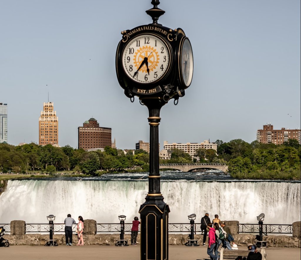 a clock on a pole in front of a waterfall